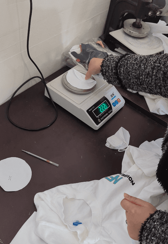 Garment quality control process in Hebei with fabric piece being weighed.