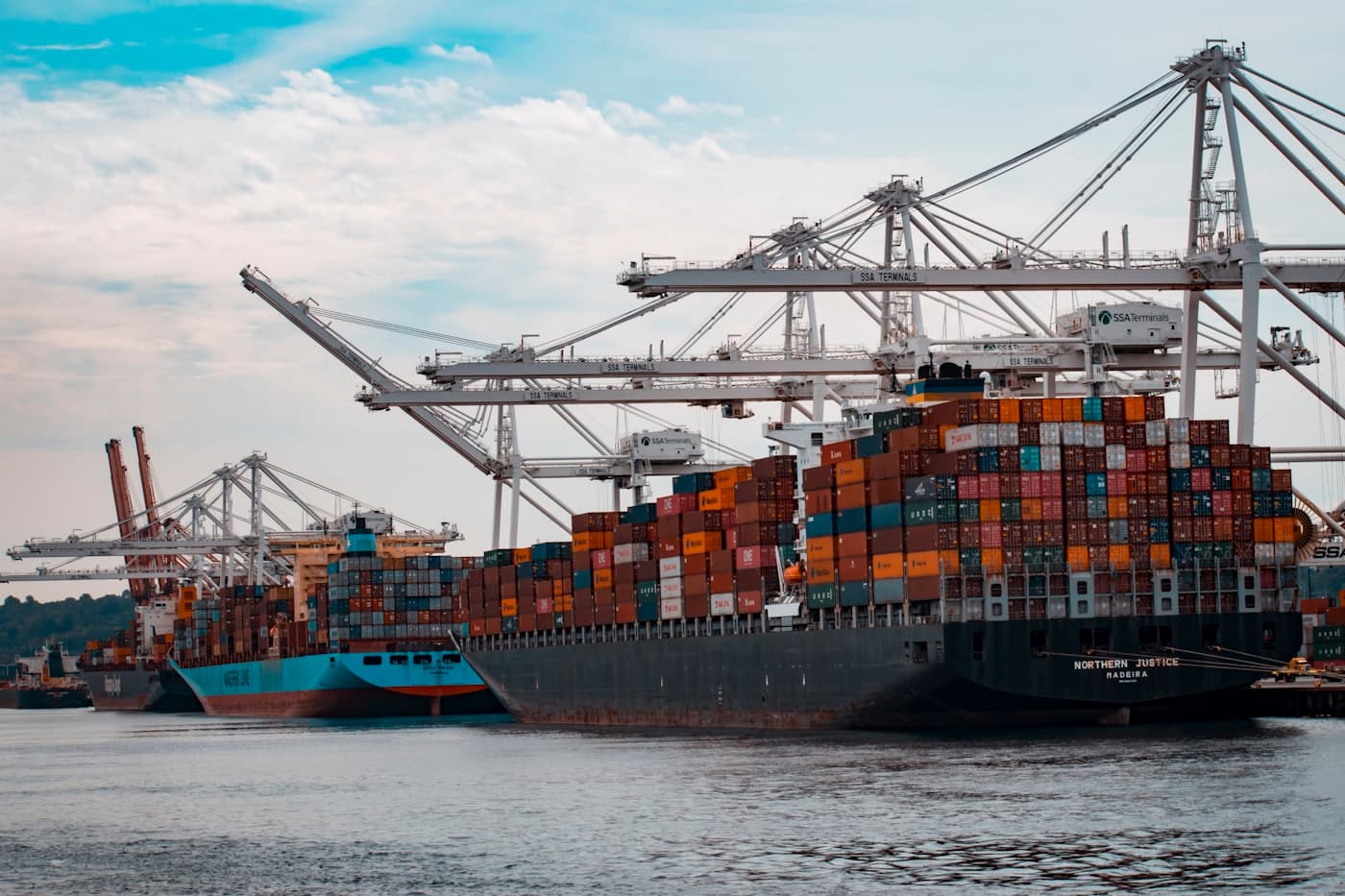 Container ships and stacked containers at a commercial port terminal, representing international commodity trade.