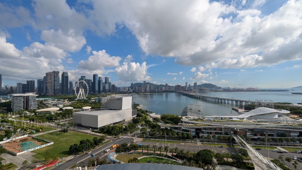 Shenzhen bay skyline and waterfront under a bright blue sky.