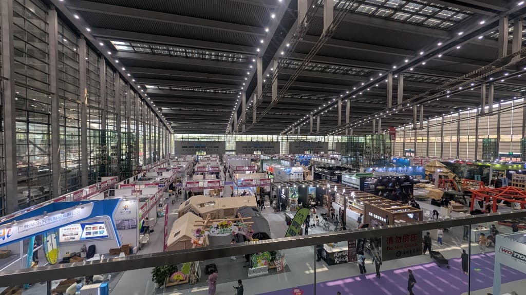 Large indoor Shenzhen trade fair hall with many supplier booths and visitors.